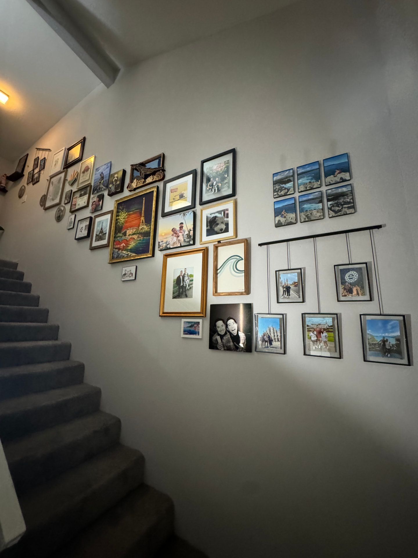 Stairway gallery wall with framed photos and art hung in a clean arrangement