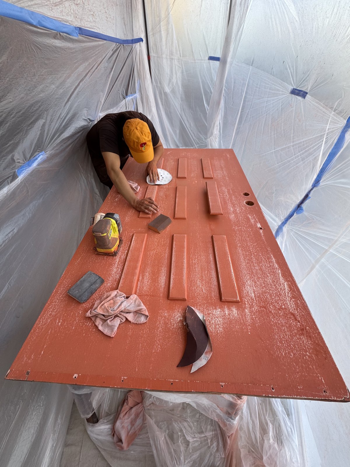 Sanding and prepping a door for paint inside a plastic dust containment
