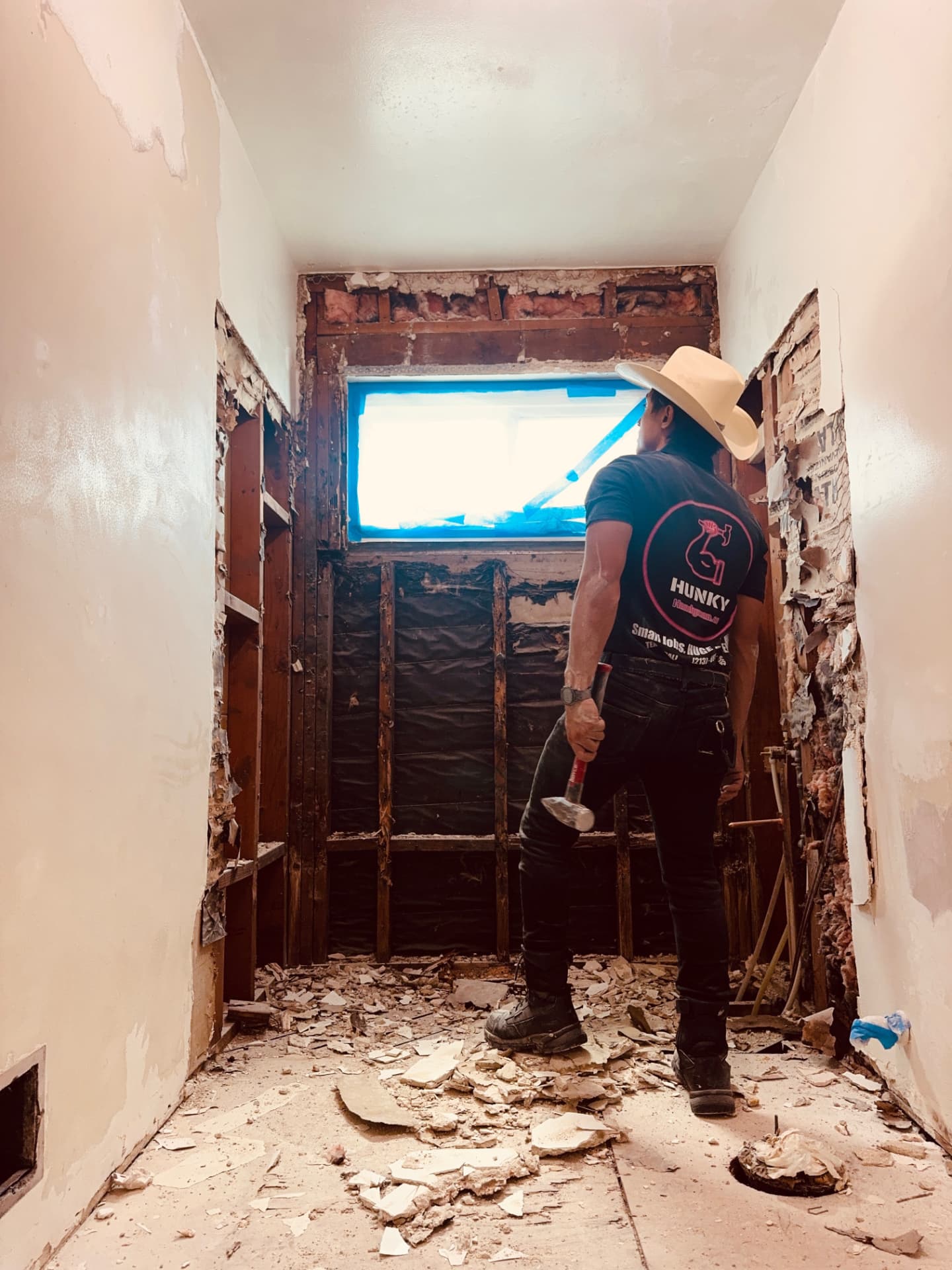 Bathroom demolition with exposed framing and Hunky Handyman crew at work