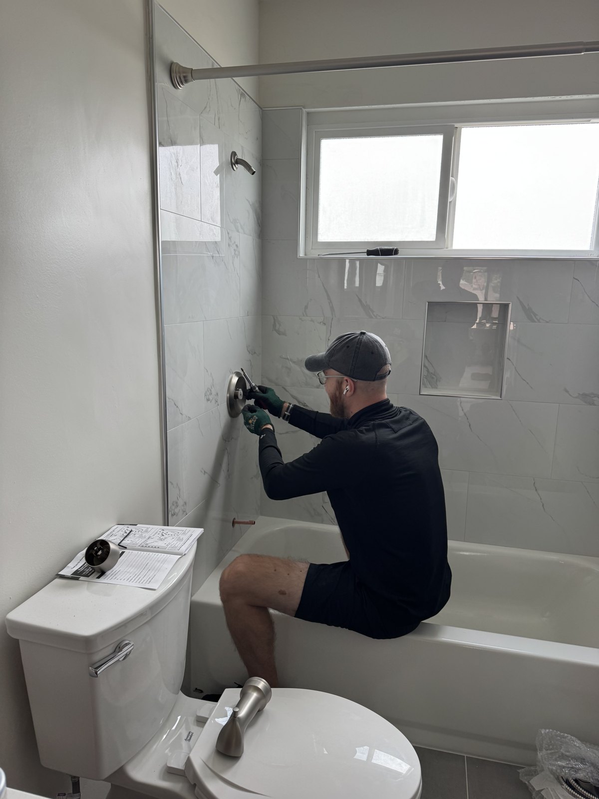 Handyman installing a shower valve trim in a newly tiled bathroom